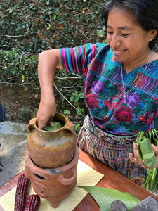 Woman in colorful traditional clothing using traditional pottery.
