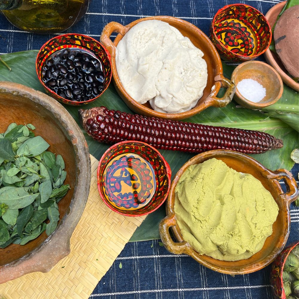 Various ingredients including beans, corn, and greens on a blue checkered tablecloth.