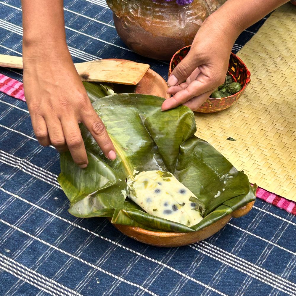 Close up of a freshly unwrapped corn tamal, revealing a bean filling and the banana leaf traditionally used for steaming and serving.