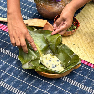Close up of a freshly unwrapped corn tamal, revealing a bean filling and the banana leaf traditionally used for steaming and serving.