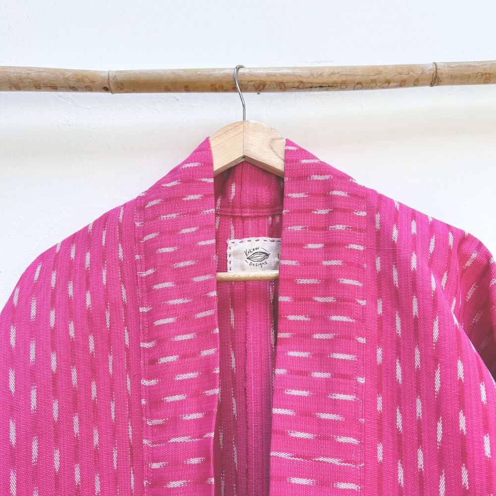 Pink jacket neck with white patterns on a wooden hanger against a white background