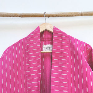 Pink jacket neck with white patterns on a wooden hanger against a white background