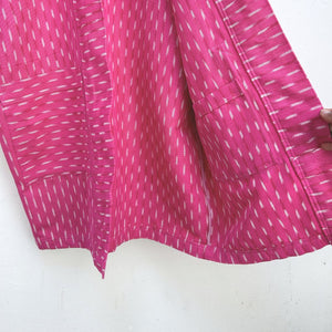 Close-up of a pink fabric with white patterns on a white background
