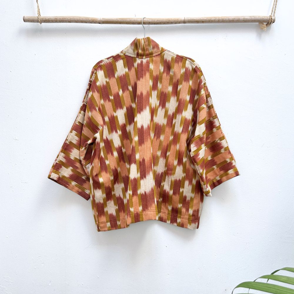 Patterned shirt hanging on a wooden rod against a white background