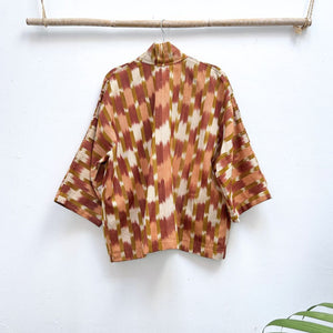 Patterned shirt hanging on a wooden rod against a white background