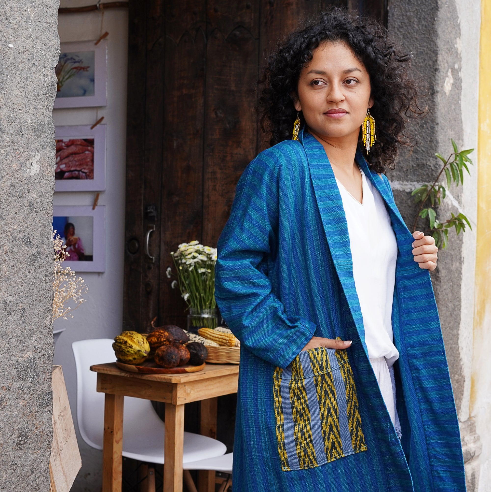 Woman wearing a blue and yellow patterned coat standing in an outdoor setting.