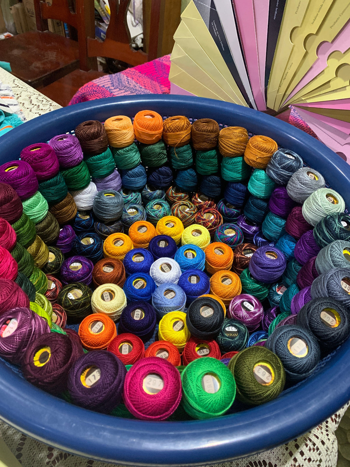 Assorted colorful spools of thread in a blue basket with a blurred background