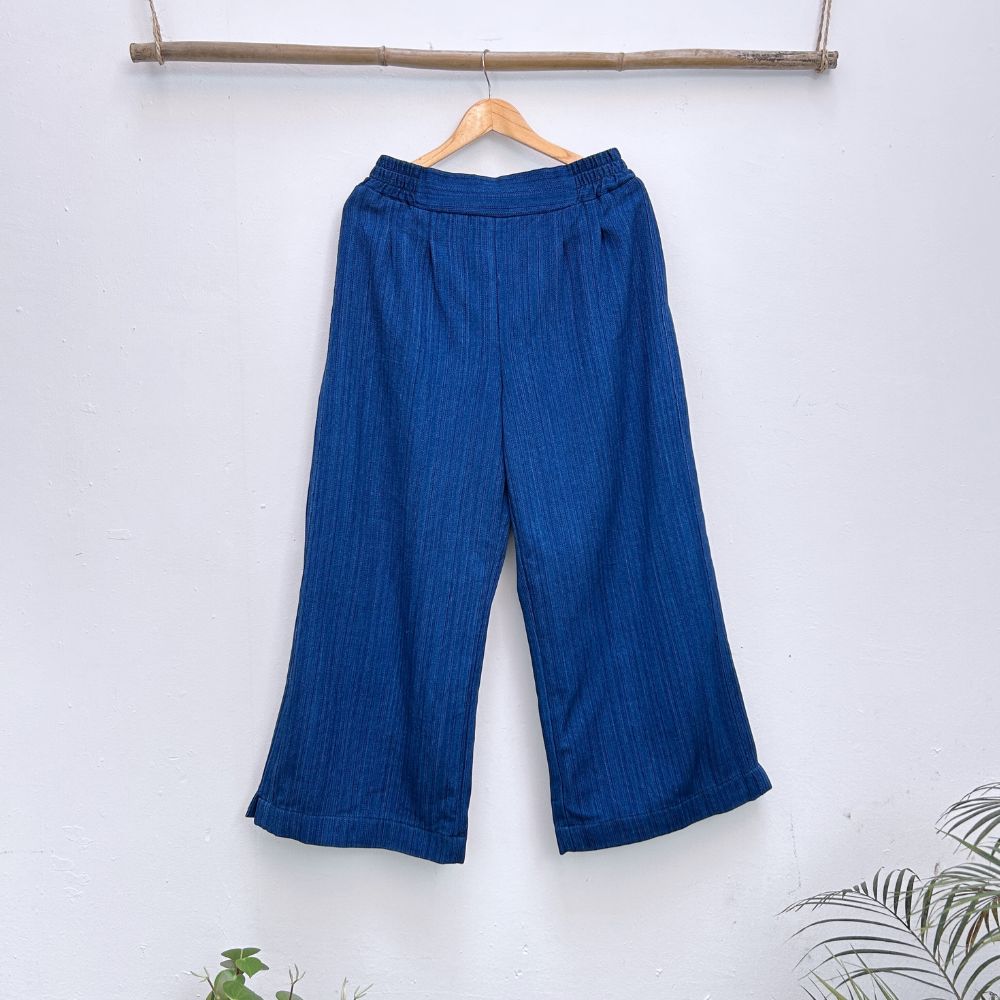 Blue pants hanging on a wooden hanger against a white background