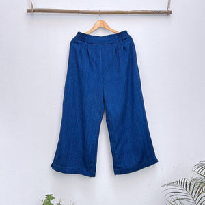 Blue pants hanging on a wooden hanger against a white background