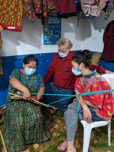 Two people looking carefully at the details of a loom's finishing
