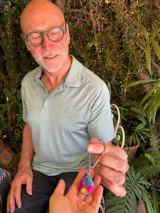 Our friend Andrew holding the pompom he made himself during the class. He is smiling broadly and proudly displaying his pompom, which features vibrant colors.