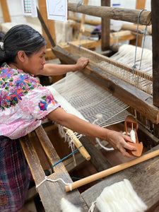 Woman weaving on a traditional loom in a textile workshop.