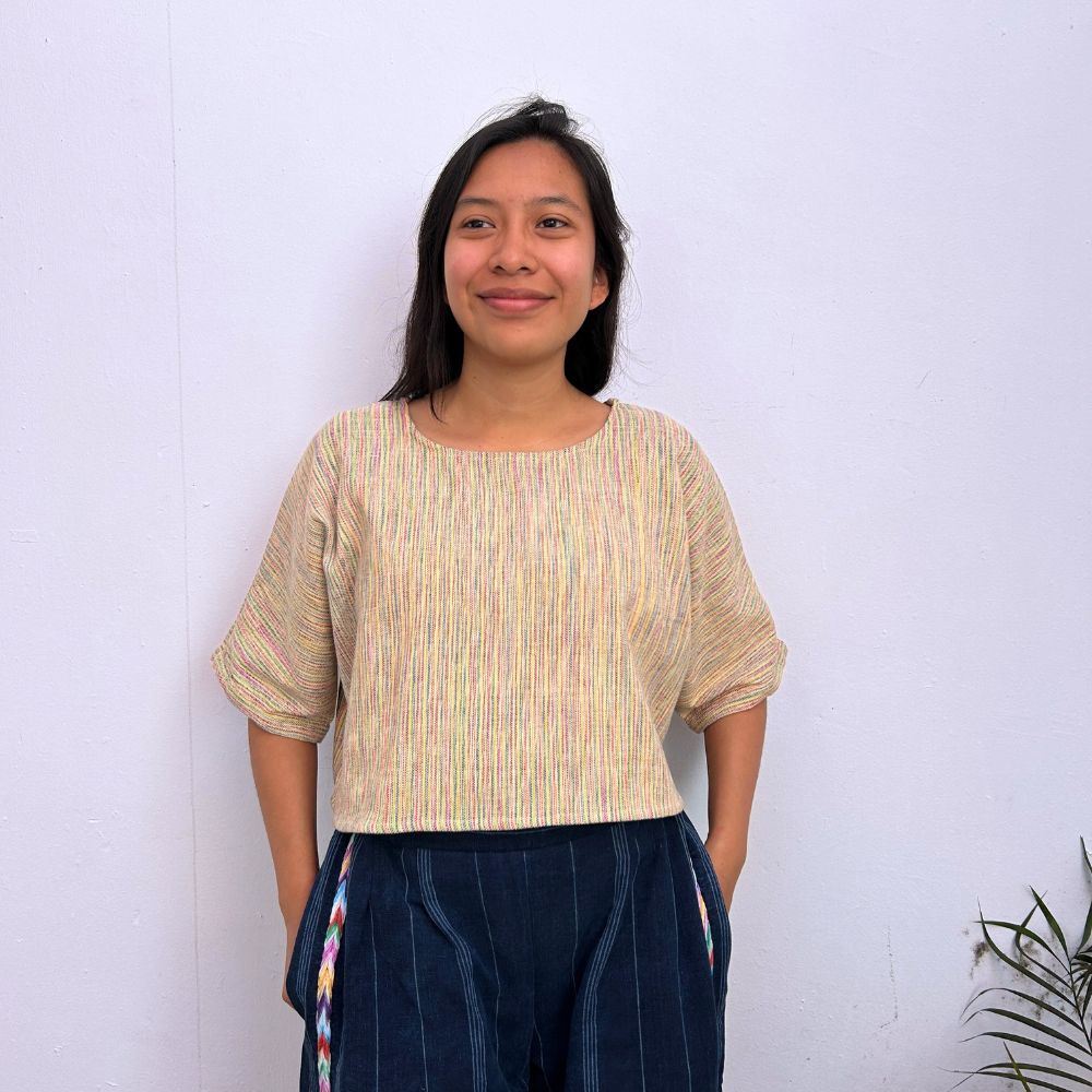Woman wearing a striped top and dark pants against a white background