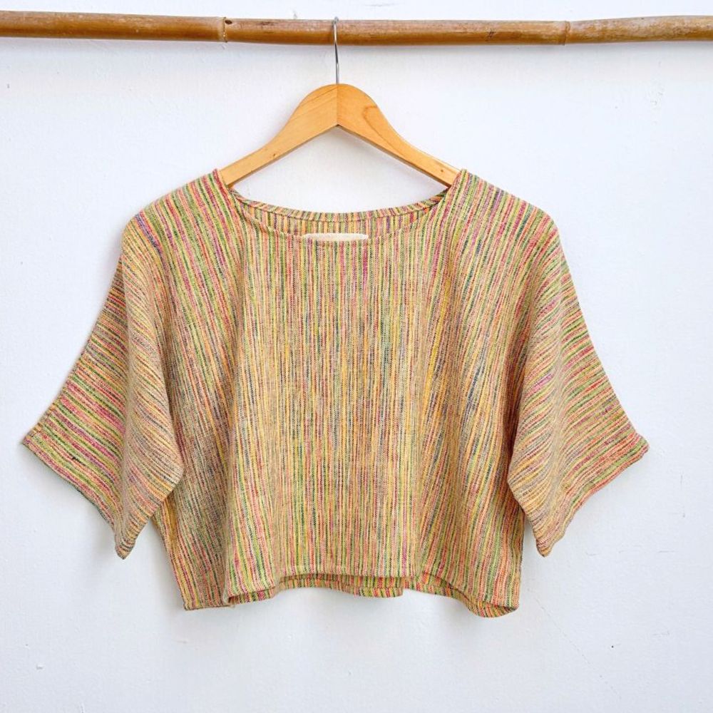 Multicolored striped top on a wooden hanger against a white wall