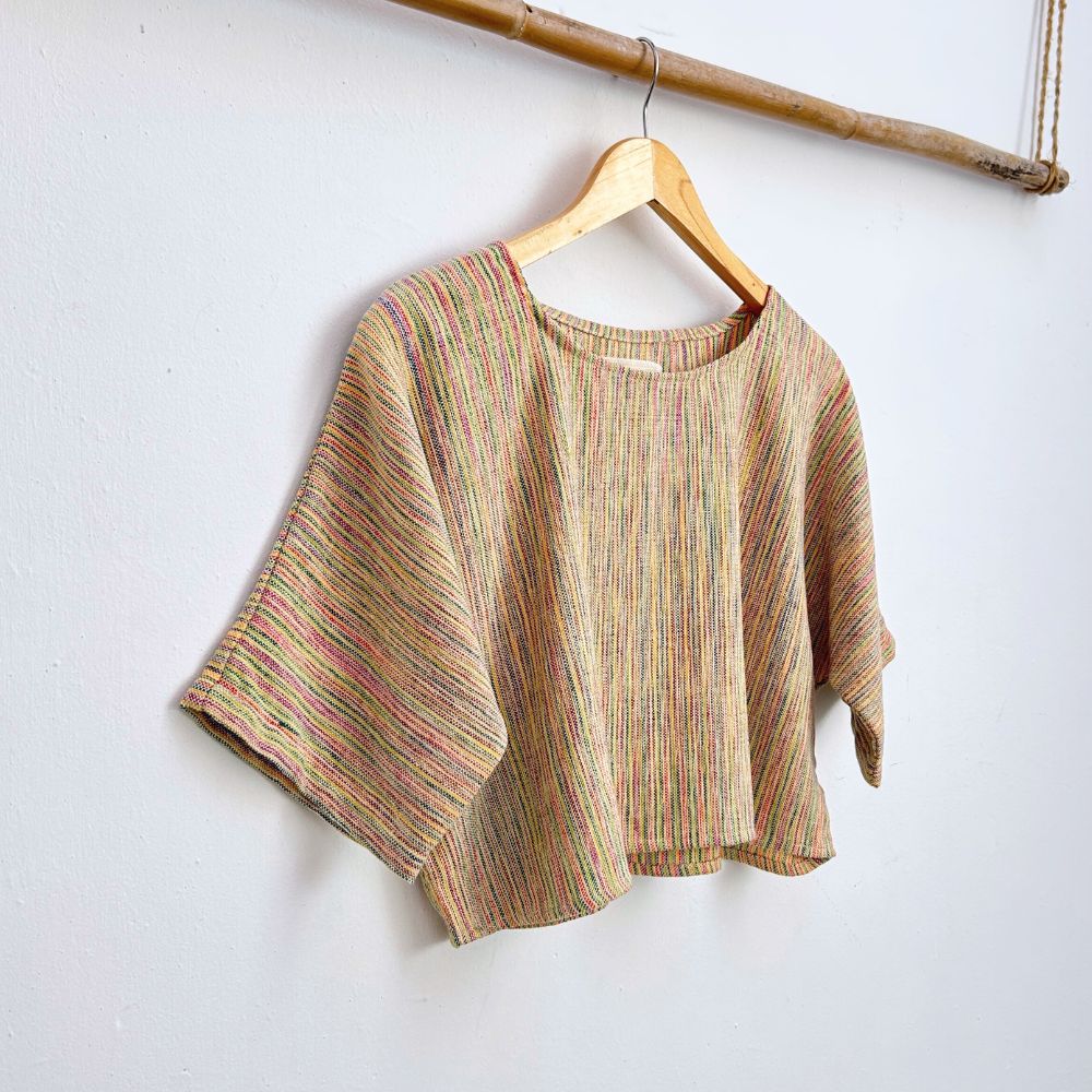 Striped colorful  top on a hanger against a white background