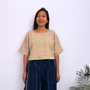 Woman wearing a multicolor top and dark pants against a white background