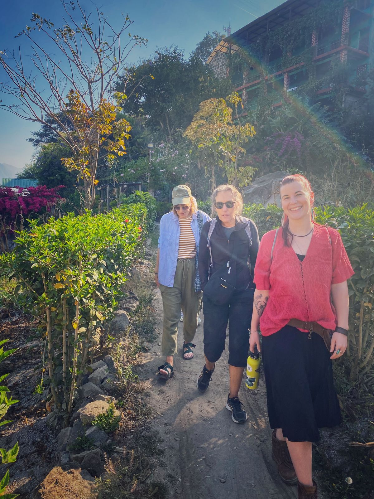 Three people standing on a path surrounded by greenery and plants at Lake Atitlán