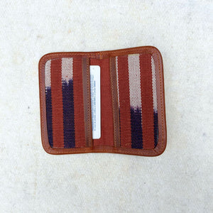 Striped cardholder with brown, blue, and white pattern with brown leather border.