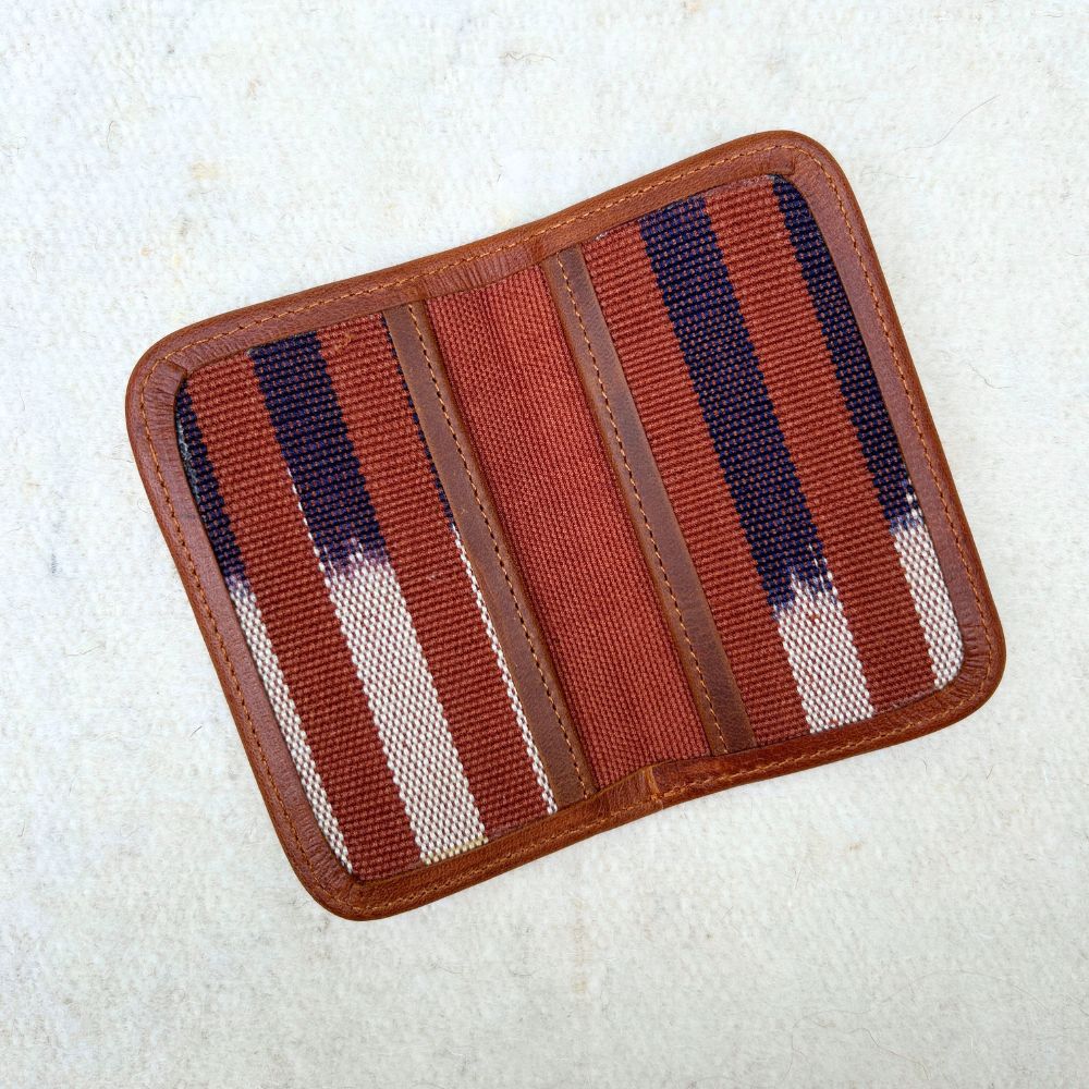 Striped cardholder with brown, blue, and white pattern with brown leather border.