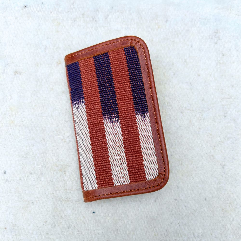 Striped cardholder with brown, blue, and white pattern with brown leather border.