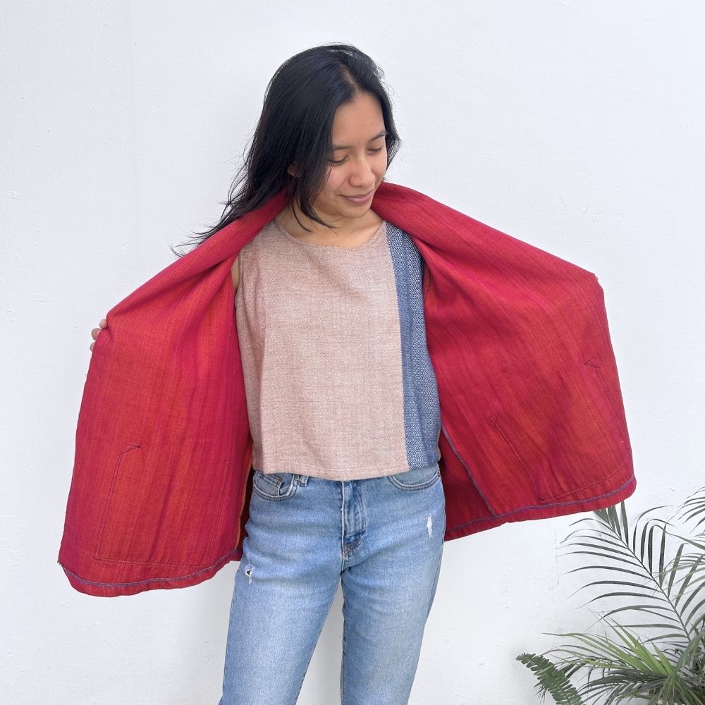 Person holding open a red jacket over their shoulders against a white background