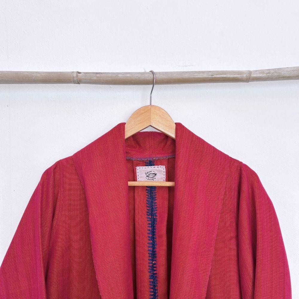 Red garment with a visible brand label on a wooden hanger against a white background