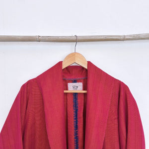 Red garment with a visible brand label on a wooden hanger against a white background