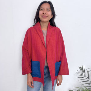 Person wearing a red and blue jacket against a white background