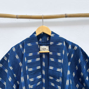 Blue and white patterned jacket on a wooden hanger against a white background