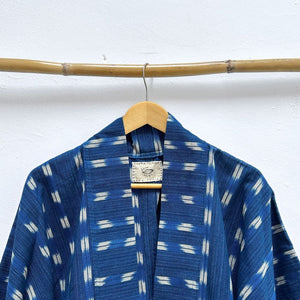 Blue patterned garment on a wooden hanger against a white background