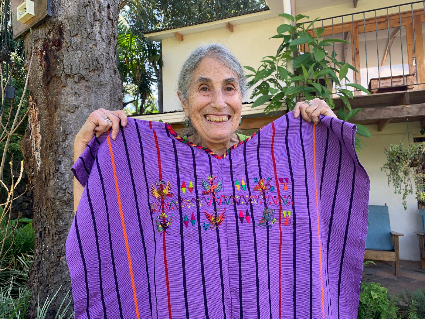 Woman holding a purple embroidered garment outdoors
