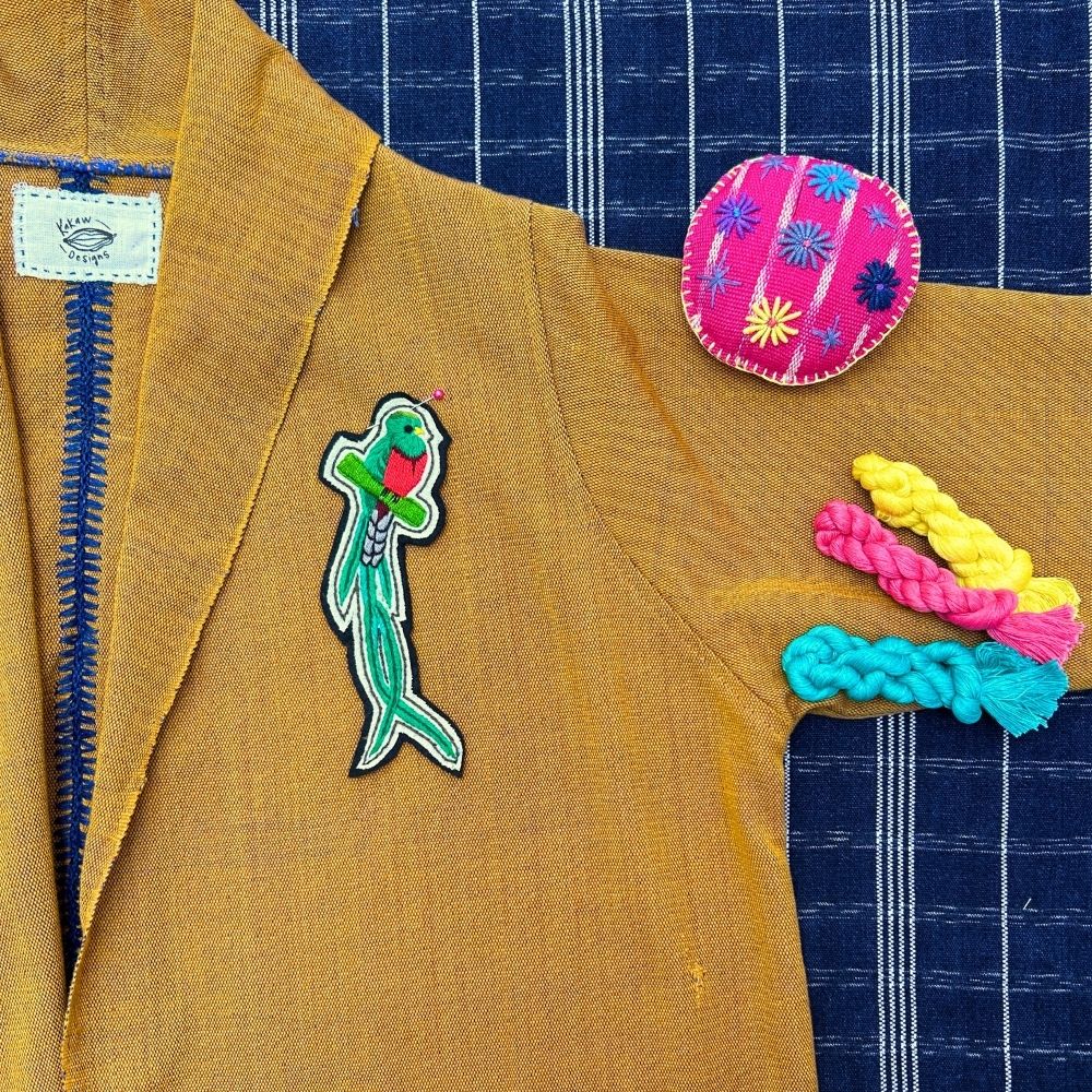Quetzal embroidered patch on a mustard jacket and pin cushion 