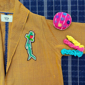 Quetzal embroidered patch on a mustard jacket and pin cushion 