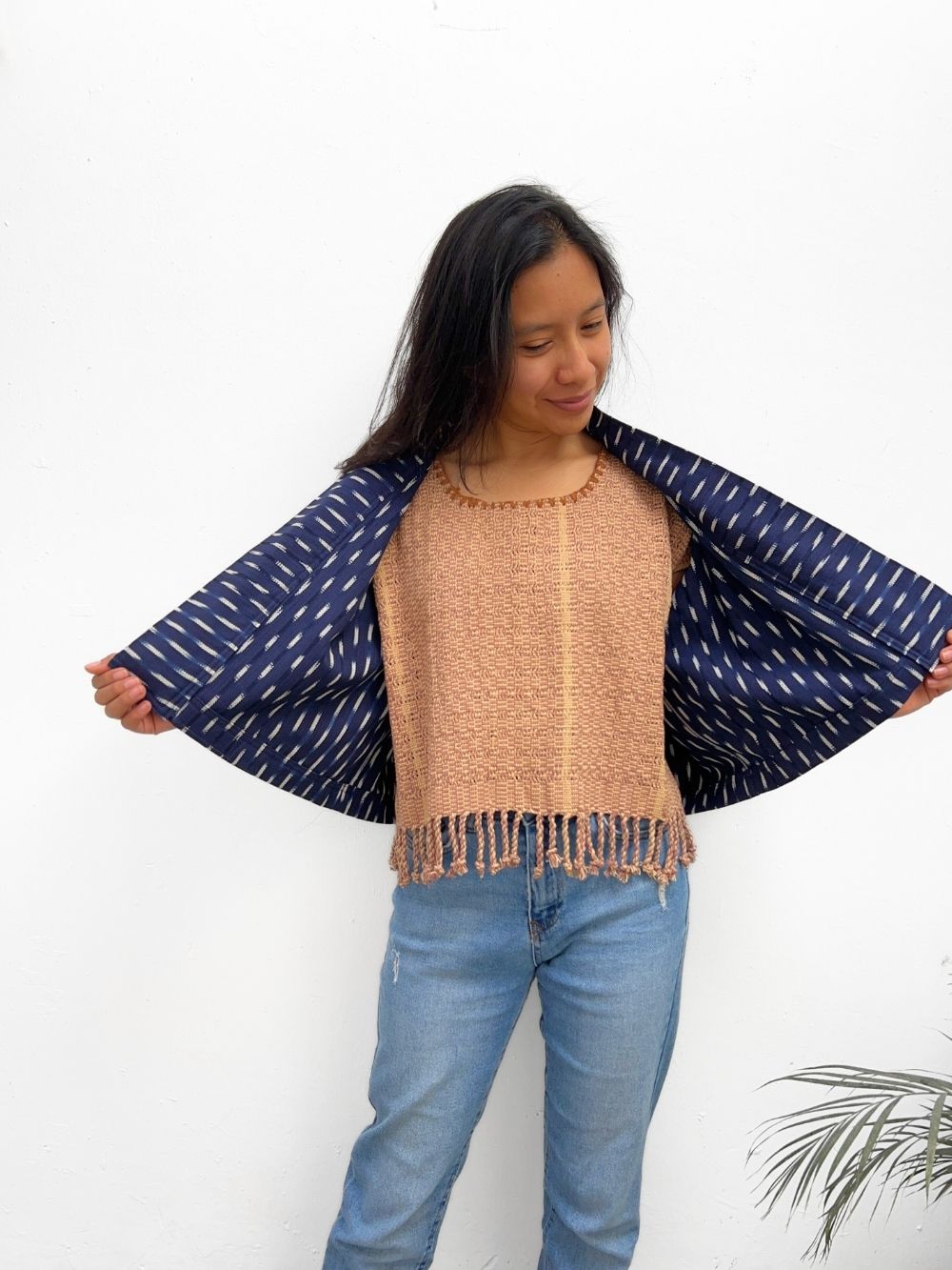 A woman wearing an Indigo blue jacket with a white ikat pattern, paired with a beige top and blue jeans.