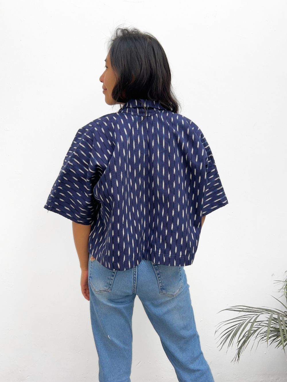  A woman wearing an Indigo blue jacket with a white ikat pattern, paired with blue jeans.