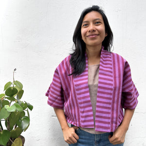 Model  wearing Two Shades of pink striped cropped jacket on a white background.