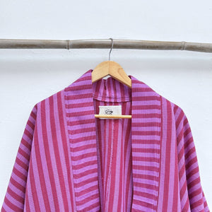 Pink and purple striped garment on a hanger against a white background